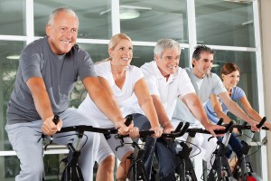 Happy senior citizens exercising in spinning class in fitness ce