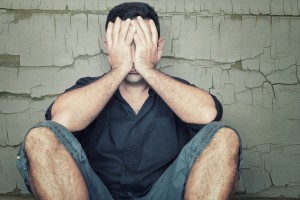 Depressed young man sitting on the floor and covering his face w