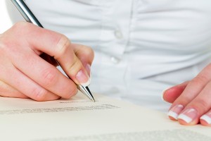 a woman signs a contract or a will with a fountain pen.